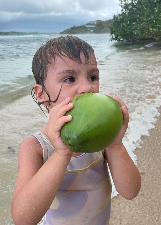 Child drinking from fresh coconut on tropical beach