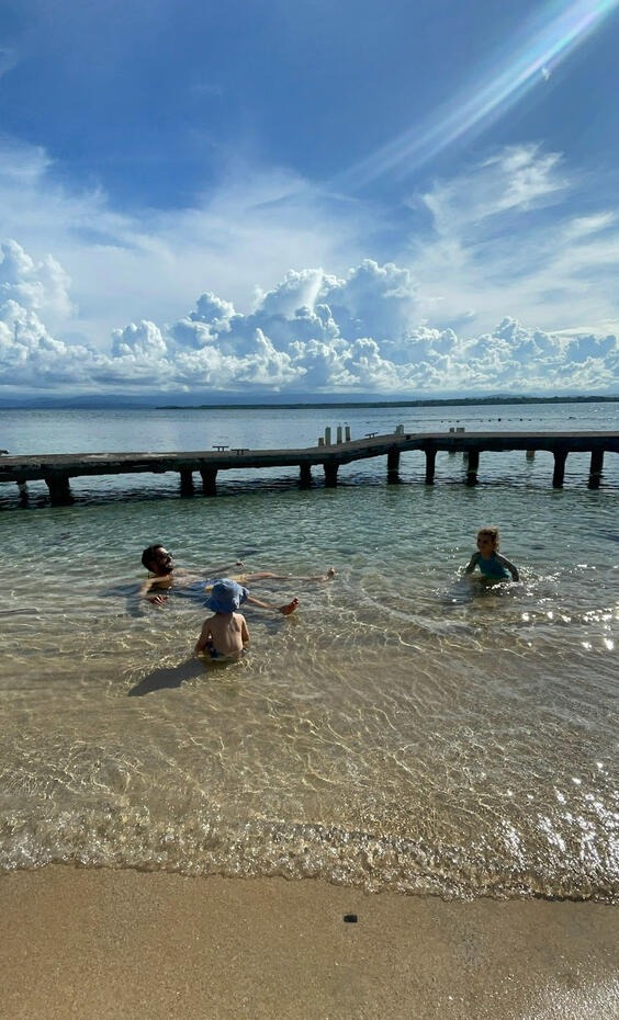 Kids swimming in calm turquoise water near wooden dock