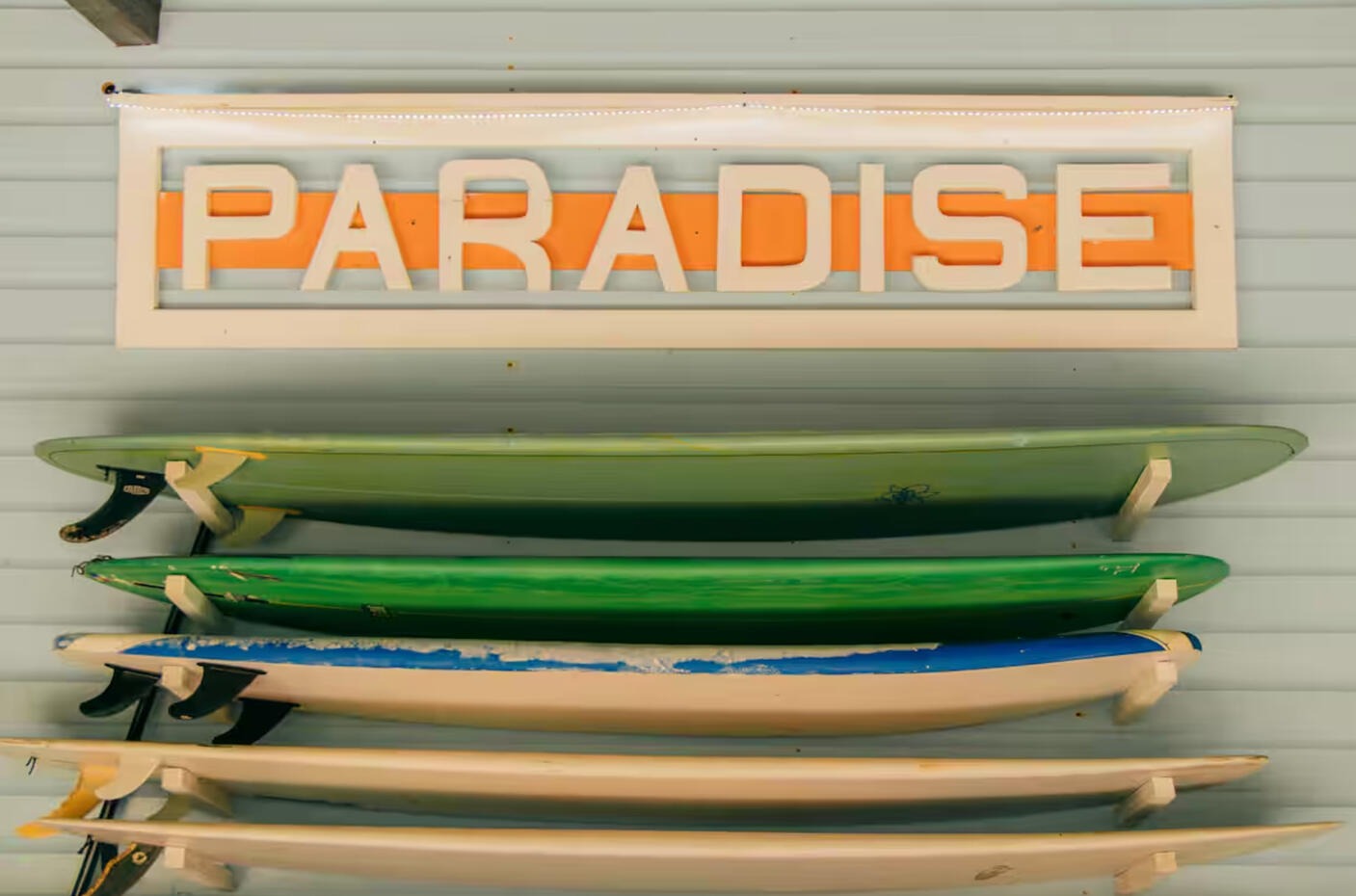Rack of surfboards with paradise sign