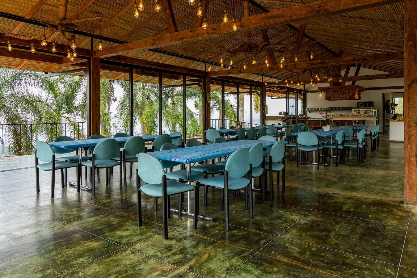 Dining hall with teal chairs and forest views at Casa Sumapaz