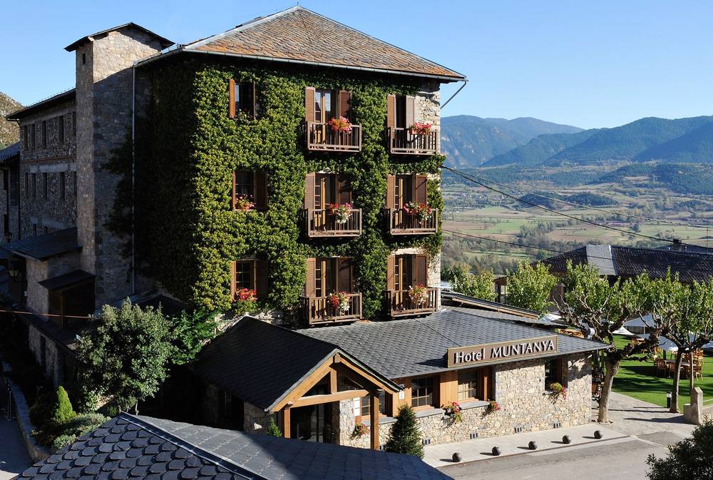 Ivy-covered stone mountain hotel at Cerdanya Viva with the valley behind