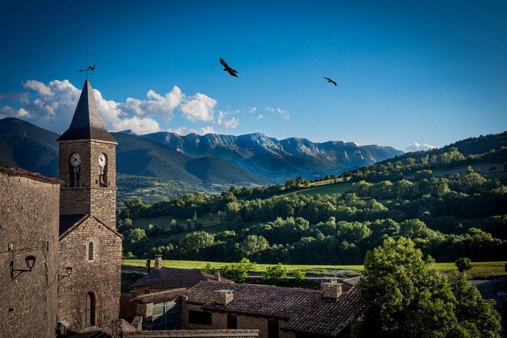 Stone village church tower with the Cerdanya valley and mountains behind