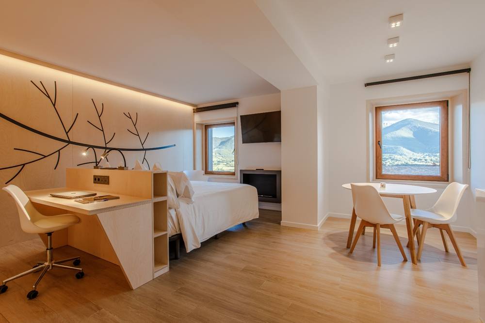 Apartment interior at Cerdanya Viva with bed, desk, dining table and mountain window