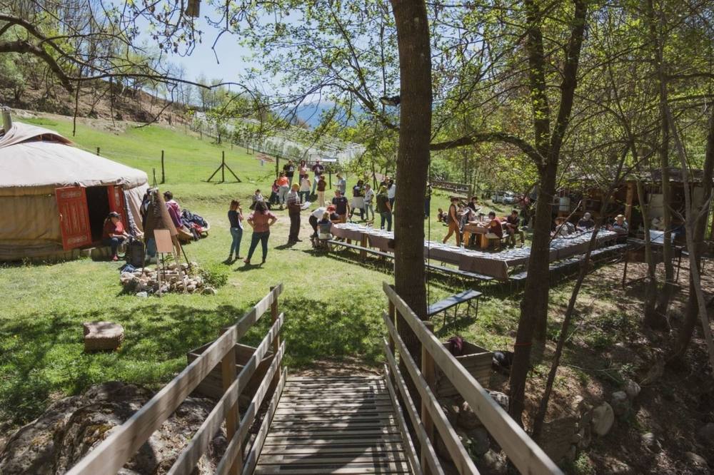 Yurt and wooden terrace on the lawn at Cerdanya Viva with people gathered