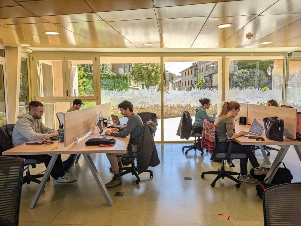 Coworking room at Cerdanya Viva with desks, laptops and windows onto the village