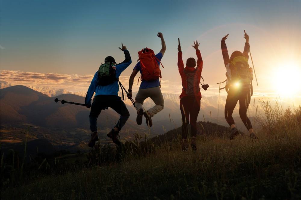 Four walkers silhouetted on a Pyrenean ridge at sunset
